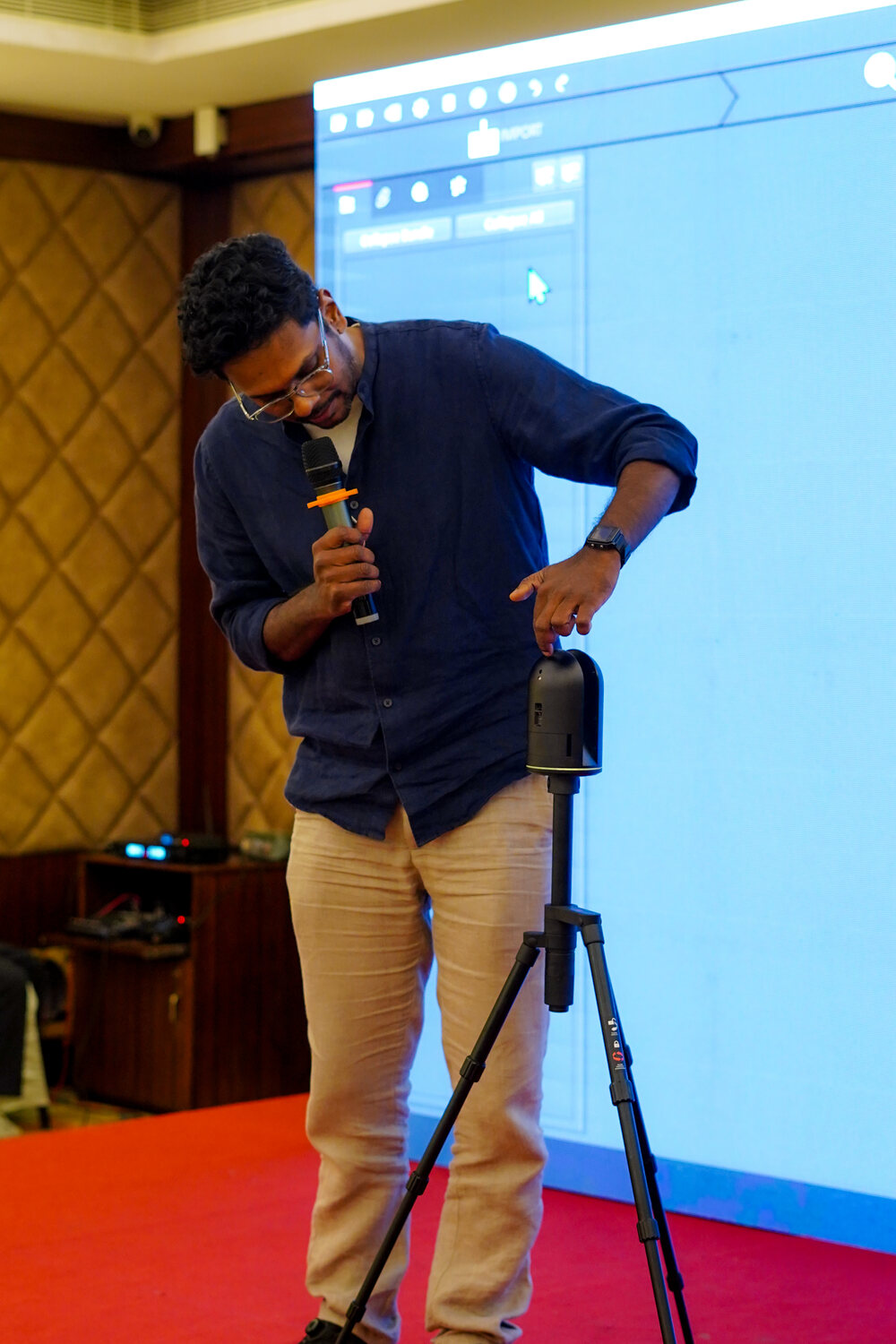 A trainer demonstrating a tripod-mounted laser scanner, with the capture software on the screen behind him