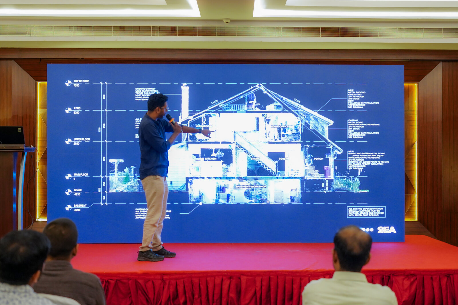 A trainer presenting a building section drawn from laser-scan point cloud data on a large screen at a Bumblebee Inc programme in Coimbatore.